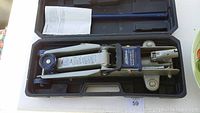 Hydraulic trolley jack placed inside black molded plastic case, showing jack details and handle.