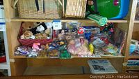 Shelf with assortment of Beanie Babies, mini dolls, teddy bears, and children's books.