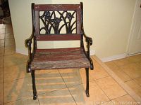 Front view of vintage cast iron patio chair with wood seat slats and decorated backrest.
