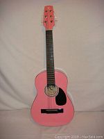 Front view of the pink acoustic guitar showing the body, strings, sound hole with Robson label, and black pickguard.