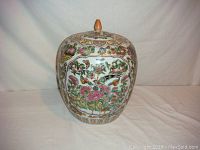Front view showing floral panels and the top lid with carved finial.