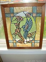 Front view of wooden-framed stained glass window panel with hummingbird design