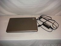 Closed HP 15-inch laptop with power adapter and charger cable shown on a white surface.