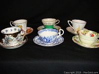Front view of 6 vintage bone china cup and saucer sets with various floral and decorative patterns.