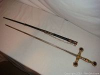 Full length view of sword laid next to black decorated sheath with chain, showing overall length and condition, visible sheath tears