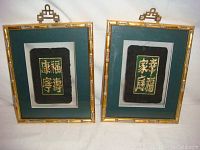 Front view of two framed original calligraphy artworks by C.T. Wong, bamboo-style gold frames, black background with gold Chinese characters, dark green and white mats.