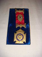 Front view of the antique sterling silver Mason medal with red ribbon, placed on blue velvet backing, showing front Masonic symbols and inscriptions.