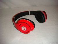 Red over-ear Beats headphones showing intact Beats logo on one ear cup and black ear cushions.