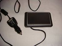Garmin Nuvi GPS device laying on a flat surface with attached car charger cable and cigarette lighter plug visible.