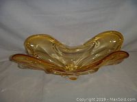 Front angle view showing the organic ruffled shape and amber coloration of the glass centrepiece.
