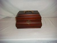 Closed tea caddy showing dark wood finish with brass handle and latch on front.