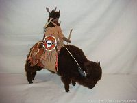 Side and front view of Native American figurine riding buffalo, showing leather clothing details and fur texture on buffalo