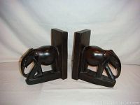 Pair of solid ebony wood elephant bookends showing right side angles and profiles.