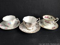Three fine bone china tea cups and saucers arranged side by side, showing unique patterns and designs.