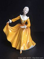 Front view of Royal Doulton Kirsty figurine in yellow dress showing detailed face and flowing skirt.