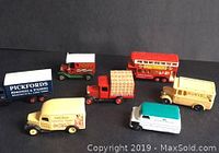 Seven die-cast model trucks and a double-decker bus arranged together showing different vintage company logos and colors