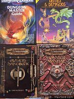 Top view showing four Dungeons & Dragons hardcover books stacked in two rows, includes Dungeon Master Guide and Deities & Demigods on top, Player's Handbook and Monster Manual below.