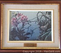Frontal photo of the framed print showing the bird, flowers, and reflections in the water, with the brass title plate visible.