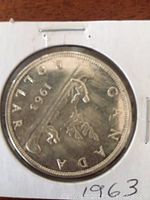 Reverse of the 1963 Canadian silver dollar showing voyageur canoe design and date.