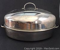 Side view of large stainless steel roasting pan with domed lid and handles on black background