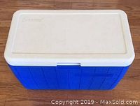 Closed Coleman cooler showing clean blue body and white lid with embossed Coleman logo.