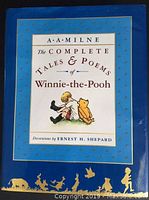Front cover of A.A. Milne's book with title and illustration of Christopher Robin and Winnie-the-Pooh