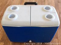 Top view of the cooler showing the white split lid with four molded cup holders on the lid corners.