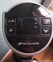 Close-up view of the Bionaire fan's top control panel showing power, speed, timer, oscillation buttons and brand logo.