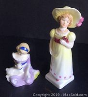 Both Royal Doulton figurines set against a black backdrop showing size and design difference