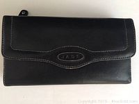 Closed black leather wallet showing 'JADE' embossed patch and white stitching on flap