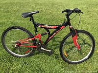 Right side view of the mountain bike on grass showing frame, tires, seat, and derailleurs.