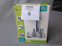 Front side of box showing 3 in 1 grooming kit with image of shaver, groomer, trimmer, and attachments, green and white box.