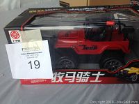 Front and side view of the boxed red RC Jeep toy car showing the brand and design through the transparent display window on the packaging.