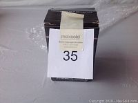 Front view of unopened black box with auction label covering