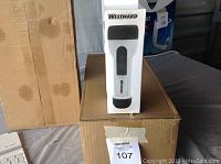 Two cardboard boxes containing 12 new Westward brand flashlights in original packaging, one flashlight box shown upright on top.