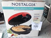 Box of Nostalgia Electric Quesadilla Maker showing product image with an open quesadilla inside and product text description.