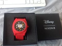 Red Nixon Mickey Mouse watch in its original black presentation box with Disney and Nixon logos.