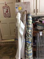 Photo showing fabric rolls standing upright against a fabric-covered board with a decorative fan cave sign in background.