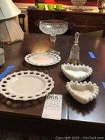 Overview of the 6 piece lot on a table, showcasing all milk glass dishes, cut glass bell, and pressed glass candy dish.
