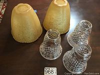 Three opaque yellowish textured glass globes and two clear globes with diamond cut and etched floral designs on table