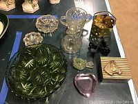 View of all ten assorted glass and metal decorative items on a table, showing bowls, figurines, and trinket boxes.