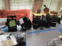 Front view showing five Polaroid Mini Portrait black cameras with rainbow stripe, arranged side by side on a table.