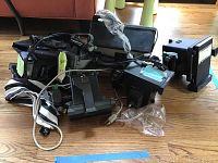 Six Polaroid cameras piled on floor showing cables and some packaging