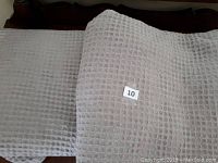 Two taupe-colored, queen-sized cotton throws with a waffle weave texture, folded and laid out.