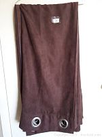 Photo of one chocolate brown drape panel showing silver grommets and fabric texture.
