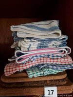 Stack of cork trivets topped by folded dishcloths and tea towels with striped and checked patterns in various colors.