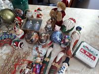 Top-side view of assorted Christmas ornaments on table including Santa, snowman, birds, beaded garland, and glass balls.