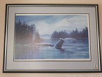 Framed limited edition print showing two humpback whales swimming in a calm, reflective water scene with forested and mountainous background.