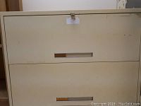 Close-up front view of the 2 drawer metal filing cabinet showing beige color and handles.