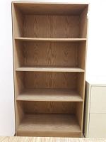 Front view of composite wood bookcase showing four shelves and wood grain finish.